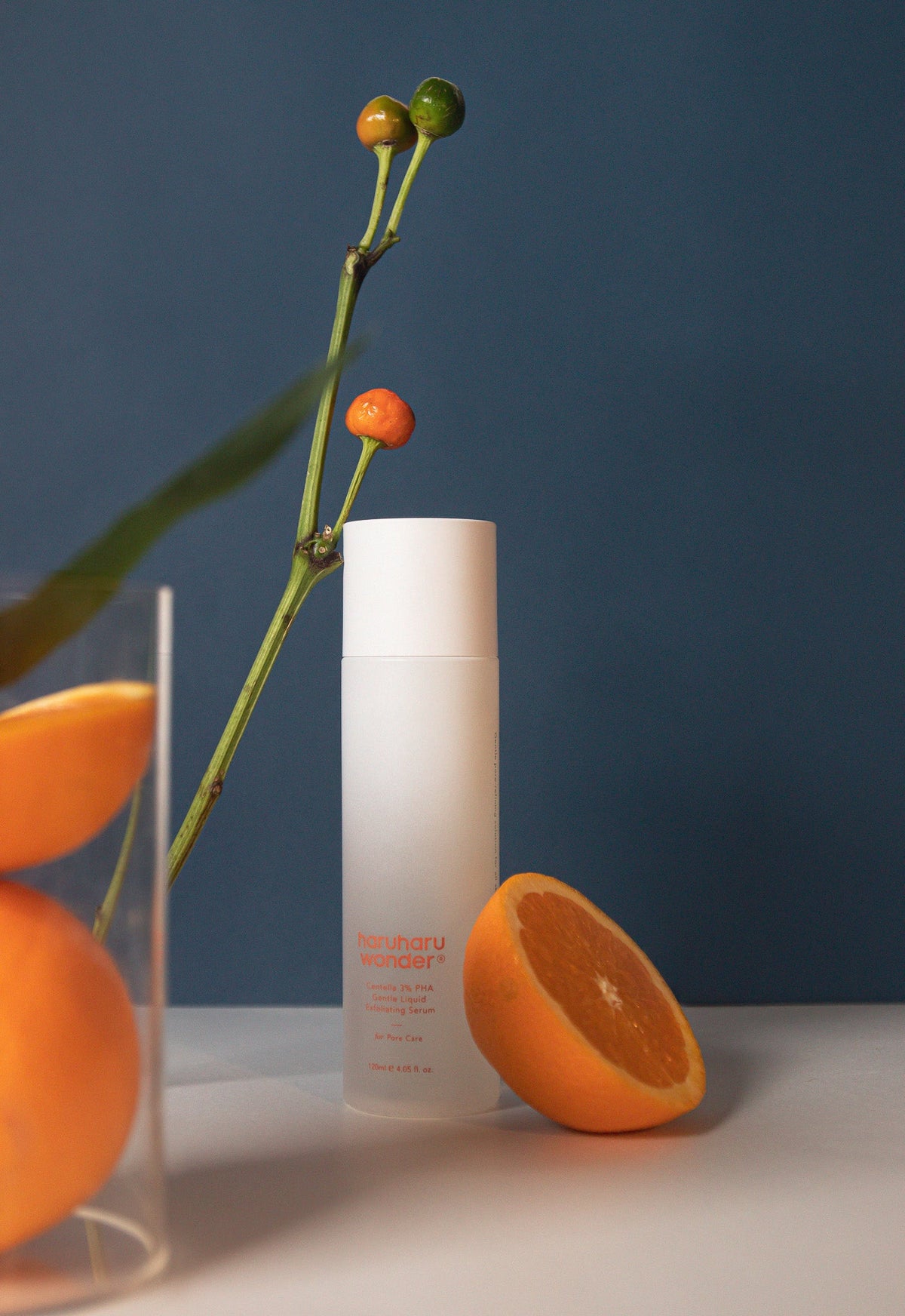 Sérum exfoliant présenté avec une demi-orange et une branche
