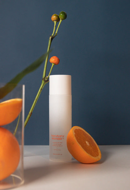 Sérum exfoliant présenté avec une demi-orange et une branche