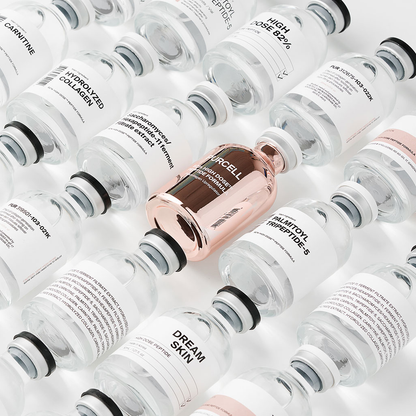 Flacon de sérum rose métallisé parmi des flacons d&