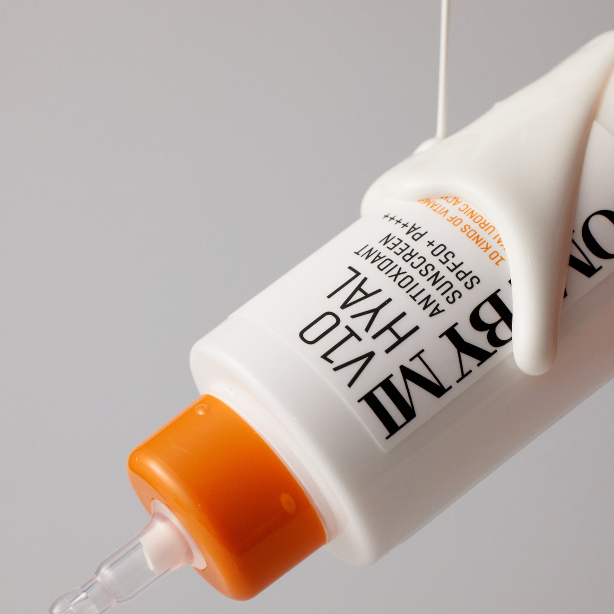 Crème solaire blanche coulant sur un tube à embout fin orange