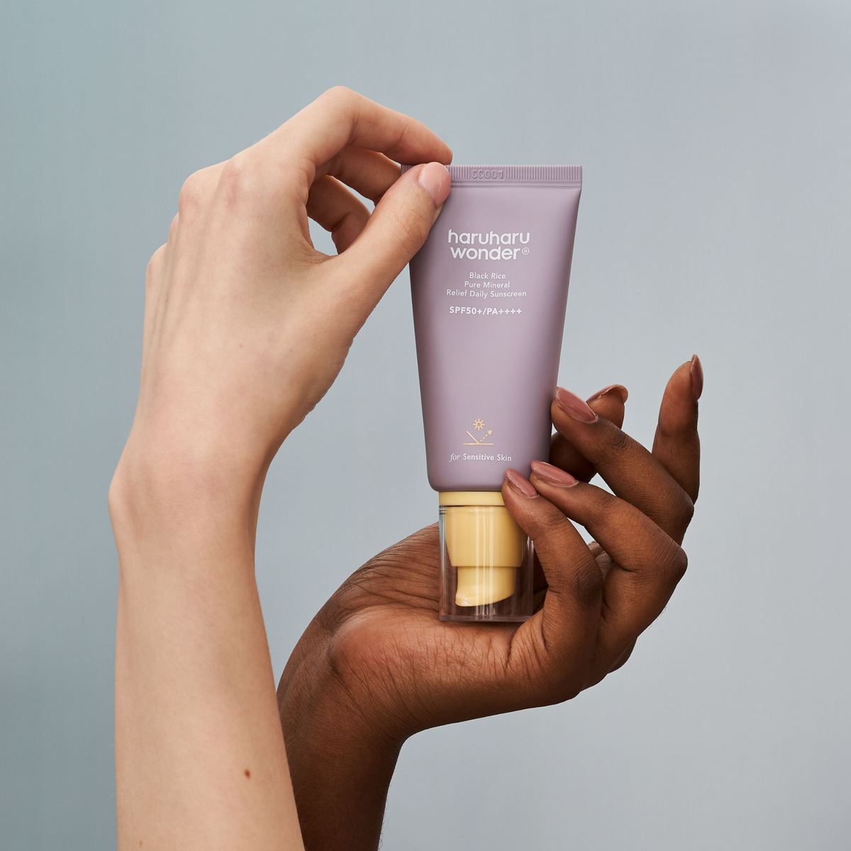 Tube mauve de solaire présenté entre deux mains