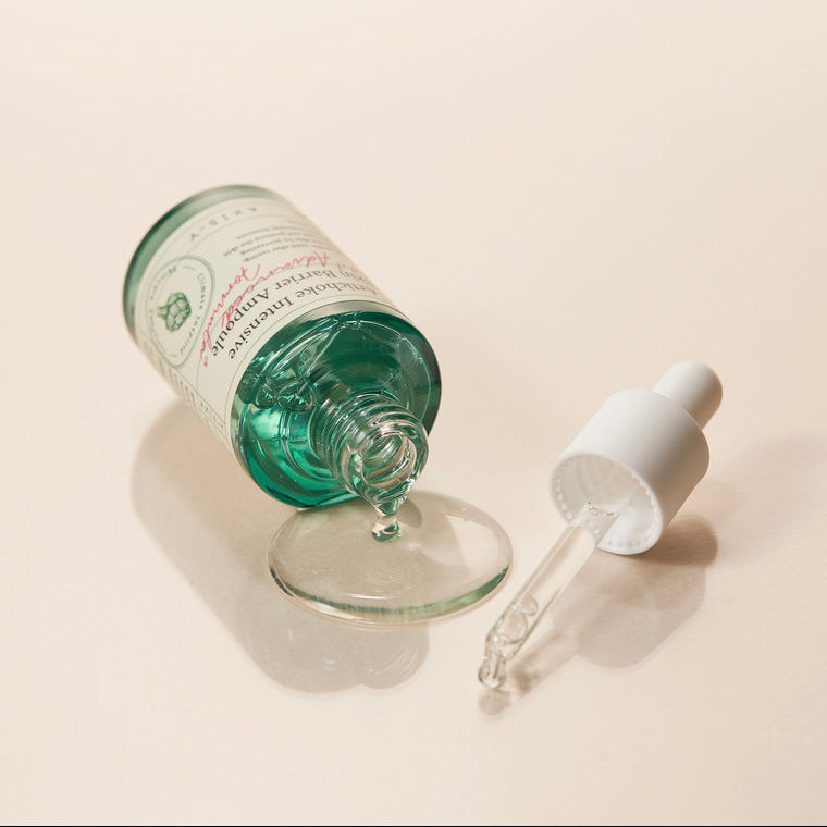 Ampoule transparente versée près du flacon ouvert et de sa pipette