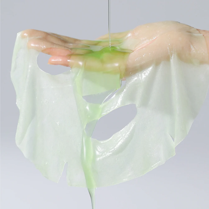 Masque en tissu imbibé de soin vert clair déplié sur la main