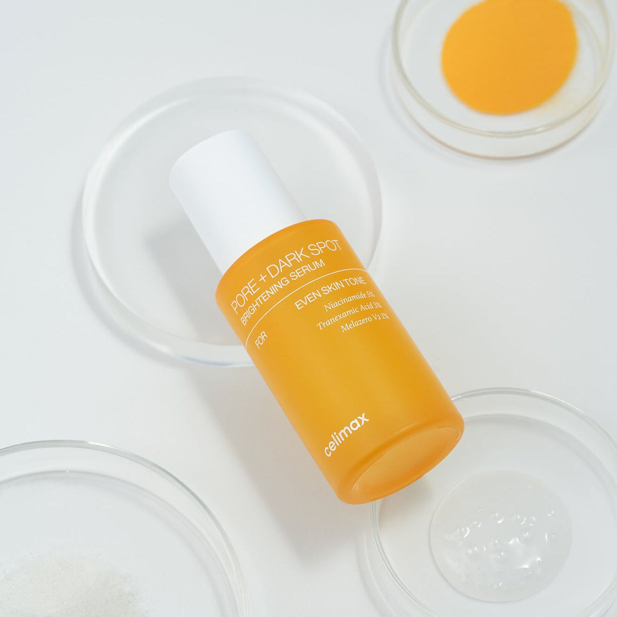 Flacon de sérum orange parmi des coupelles de soin