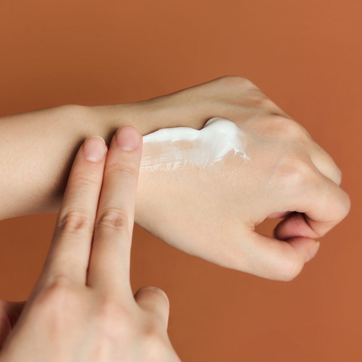 Crème blanche étalée avec deux doigts sur le dos de la main