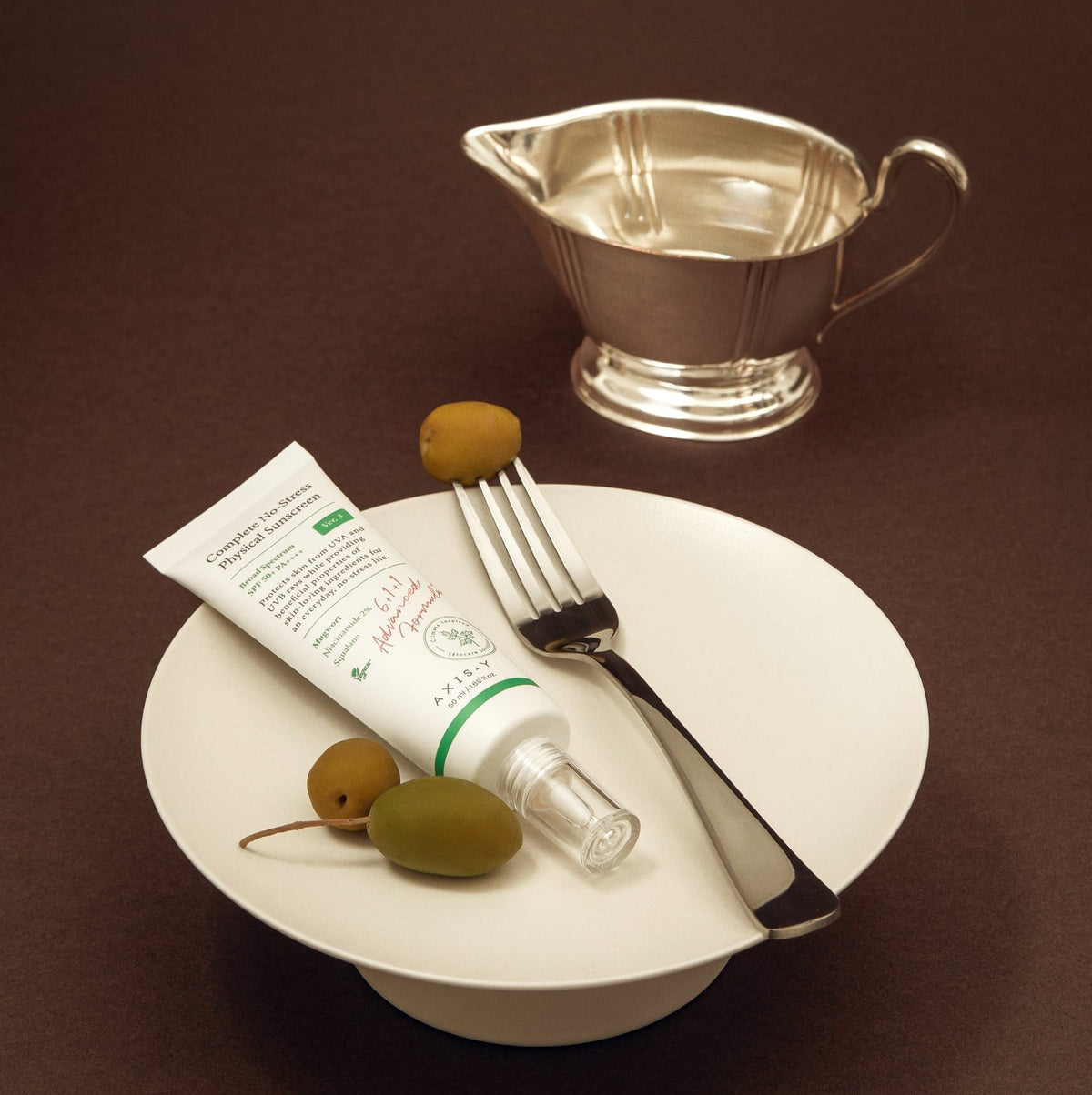 Tube de crème solaire sur une assiette avec des olives et une fourchette